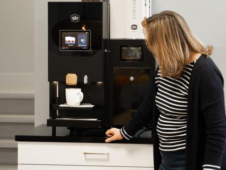 Docent pakt een kop koffie bij Gio Coffee koffiemachine